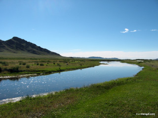 River lush green field mountain - a mountain range in the distance free wallpaper