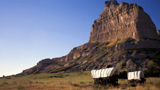Covered wagons field mountain rock - a large rock formation in the background free wallpaper
