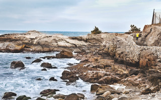 Man standing rocky cliff ocean - a surfboard free wallpaper for desktop