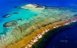 Aerial coral reef island ocean - a small island in the middle of the water free wallpaper