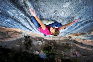 Woman climbing rock face outstretched - kai carpenter free wallpaper