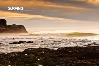 Surfer wave rocky shore cityscape - a surfer free wallpaper for desktop