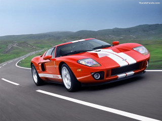 Red sports car driving road 13 - a green hillside in the background free wallpaper