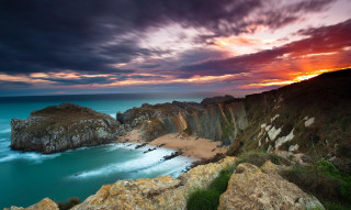 Sunset rocky beach water cliff - a sunset over a rocky beach free wallpaper for desktop