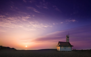 Small white building beach purple - a sun setting behind free wallpaper