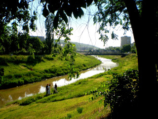 People walking green field river - a bridge in the distance free wallpaper for desktop