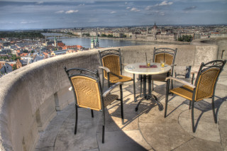 Table chairs balcony cityscape river - a view of a city free wallpaper