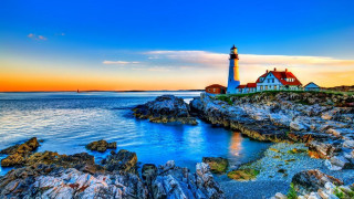 Lighthouse rocky shore sunset background - a sunset in the background and a body of water free wallpaper