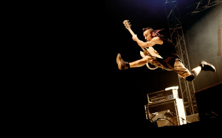 Man jumping stage guitar microphone - free bird wallpaper