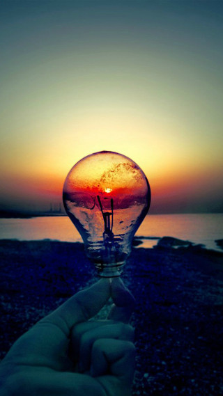 Hand lightbulb sunset water background - free light wallpaper for mobile
