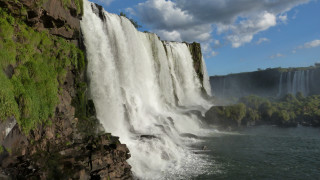 Waterfall cliff mountain lake forest - a boat in the foreground free wallpaper
