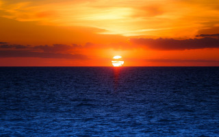 Sunset ocean boat orange sky - a boat in the distance free wallpaper