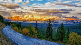 Mountain road clouds trees sunset - a mountain in the background free wallpaper