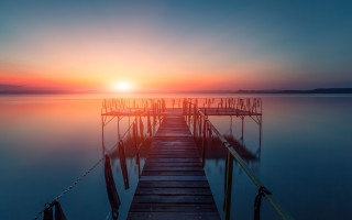 Dock sunset water gradient sky - a sunset in the background and a body of water free wallpaper