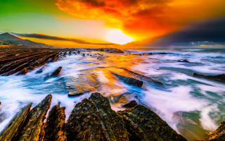 Sunset rocky beach waves mountain - a mountain in the distance free wallpaper