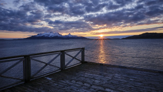 Wooden deck water mountains sunset - a sun setting free wallpaper