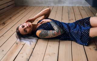 Tattooed woman laying on wooden - a wooden floor free wallpaper