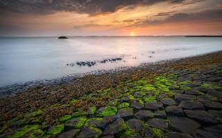 Sunset water rocks grass island - a small island in the distance free wallpaper