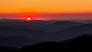 Sunset mountain range bright orange - a hazy sky in the background free wallpaper