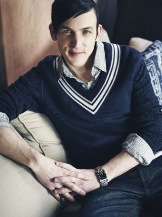 Man sitting couch sweater smile - free dark wallpaper for mobile