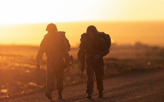 Soldiers dirt road sunset backlit - the sun setting behind them free wallpaper for desktop