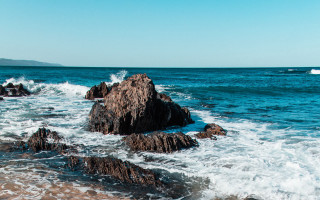 Rocky shore waves boat sky - a boat in the distance free wallpaper