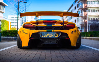 Yellow sports car brick road - tall building free wallpaper
