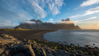 Rocky beach mountain water cloudy - a mountain in the background and a body of water free wallpaper