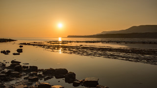 Sunset rocky beach mountain horizon - a sunset over a rocky beach free wallpaper