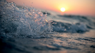 Wave breaking beach sunset ocean - the sun in the distance behind free wallpaper