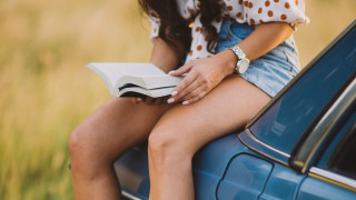 Woman sitting on car reading - a book in her hand free wallpaper