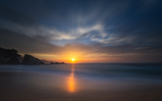 Sunset beach water rock outcropping - a sunset over a beach free wallpaper