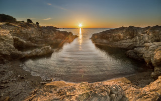 Sunset water rocks cliff scene - a sunset over a body of water free wallpaper