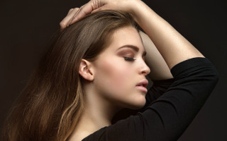 Woman long hair touching head - against a black background free wallpaper