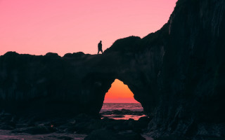 Person standing rock formation sunset - a rock formation free wallpaper