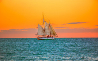 Sailboat sunset water reflection mountain - a red sky in the background free wallpaper