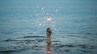 Hand sparkler water sky beach - a hand holding free wallpaper