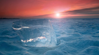 Ice sculpture sunset mountains ocean - a bright sun in the distance free wallpaper
