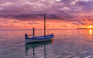 Small boat water reflection sunset - water under a cloudy sky free wallpaper