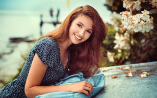 Woman bench flowers lake smile - a boat in the distance free wallpaper