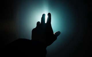 Hand raising dark light hologram - the light free wallpaper