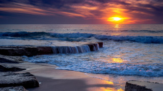 Sunset ocean waves rock wall - a sunset over the ocean free wallpaper