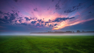 Mystical cloudy sky green field - a bench in the middle of it free wallpaper
