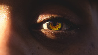 Woman eye yellow iris hyperrealism - a black background behind her free wallpaper