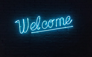 Neon welcome brick wall dark - temporary art free wallpaper