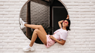 Woman pinkshirt whitesneakers windowsill lookingout - full body portrait free wallpaper