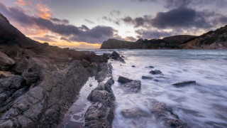 Rocky shore sunset waves mountains - a sunset in the background and a body of water free wallpaper