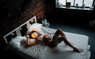 Woman laying bed brick wall - exquisite lighting free wallpaper