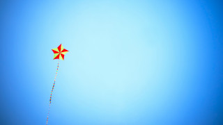 Red yellow kite flying blue - a blue sky background free wallpaper for desktop