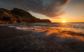 Sunset beach waves rock island - a small island in the distance free wallpaper